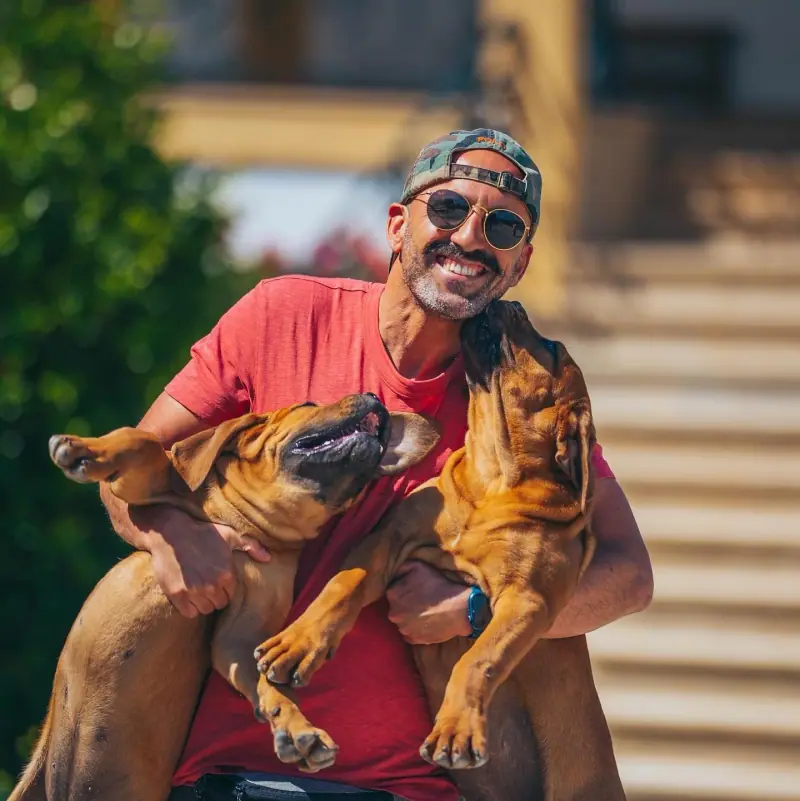 Rui Navarro holding two young Boerboels outdoors.