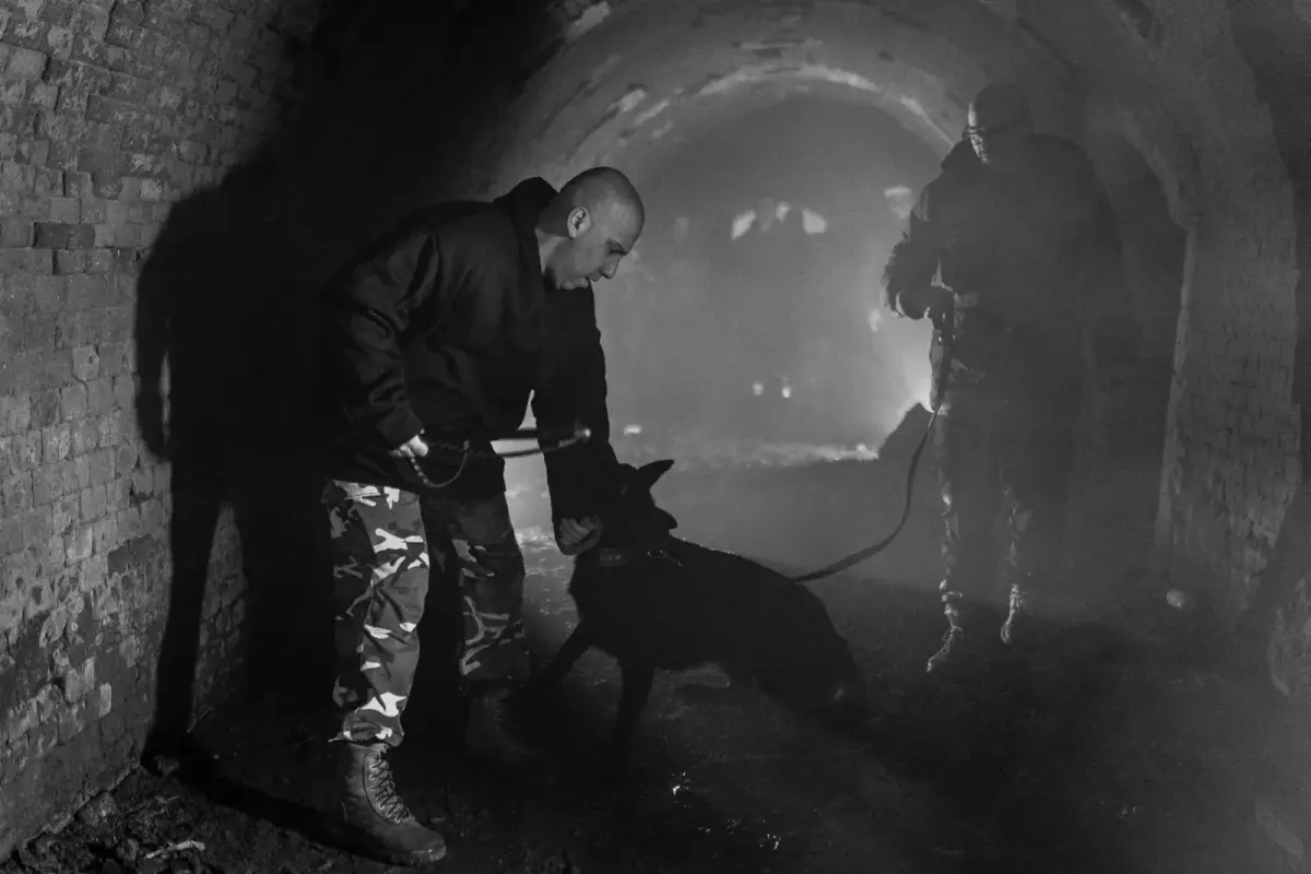 Rui Navarro from behind, black and white, with his German Shepherd Atilla in a tunnel